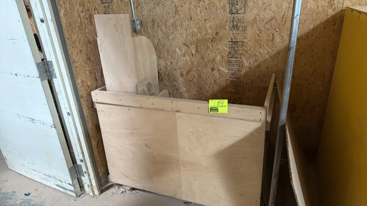Wood storage rack with contents. Features plywood construction and open top compartment. Includes assorted wood cutouts, boards, and pieces. 45"W.