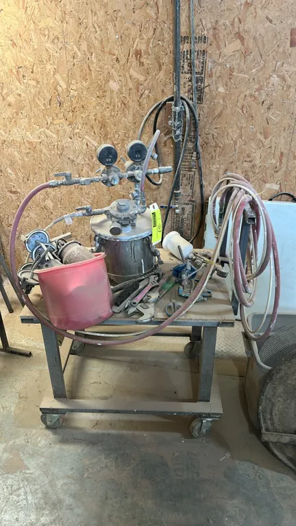 Industrial paint pressure pot setup. Includes pressure pot with dual air regulators and gauges, hoses, spray guns, paint cups, and assorted hand tools