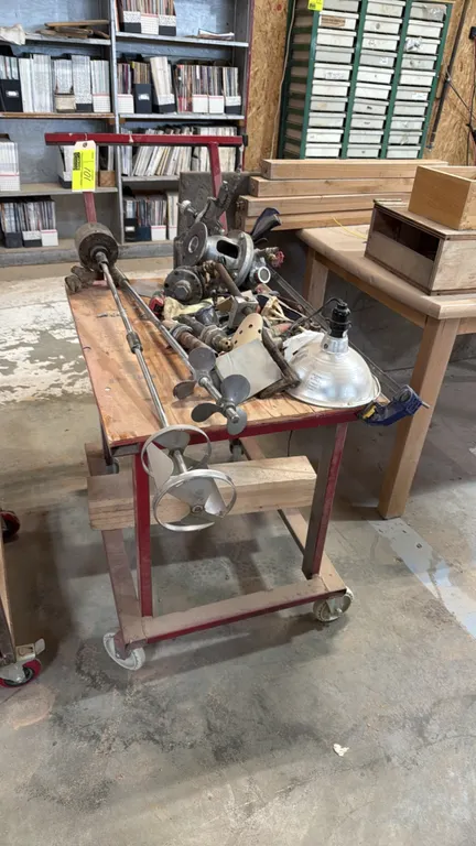Metal utility cart with assorted shop and mixer parts. Features steel frame, wood top surface, push handle, and swivel casters. Includes pneumatic spr