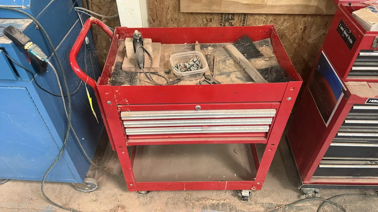 Rolling metal tool cart with contents. Features 3 slide-out drawers with aluminum pull trim, keyed lock, open top storage tray, lower utility shelf, a