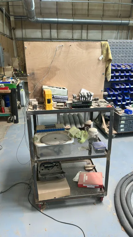 Metal 3-tier mobile shop cart. Features expanded metal lower shelves, top shelf with vertical wood partition, and swivel casters. Includes drill bits,