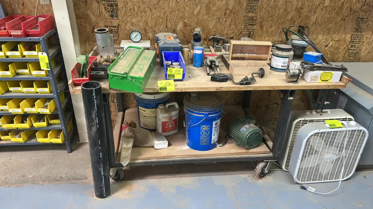 Portable 2-tier shop table. Features a wood top surface, lower storage shelf, and metal frame. 72" x 32". Mounted on swivel casters. Contents not incl