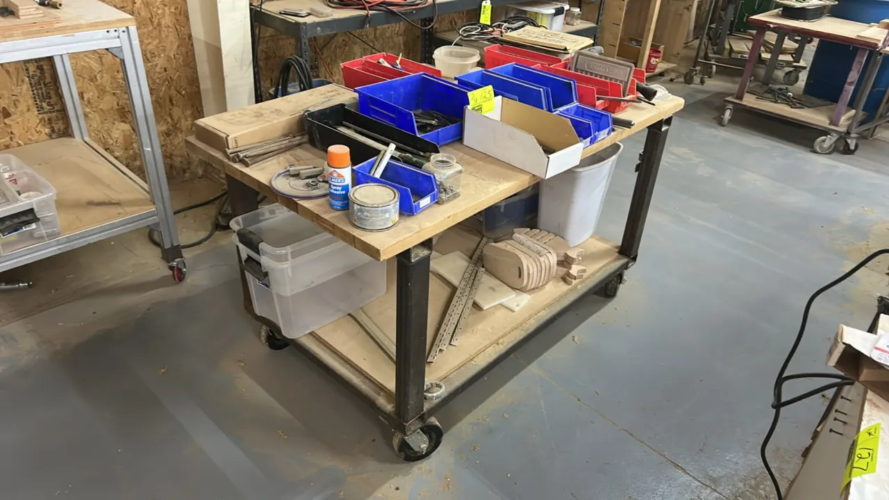 Two-tier portable work table. Features a butcher block wood top, lower wooden shelf, and steel frame. 60" x 32". Mounted on casters. Contents not incl
