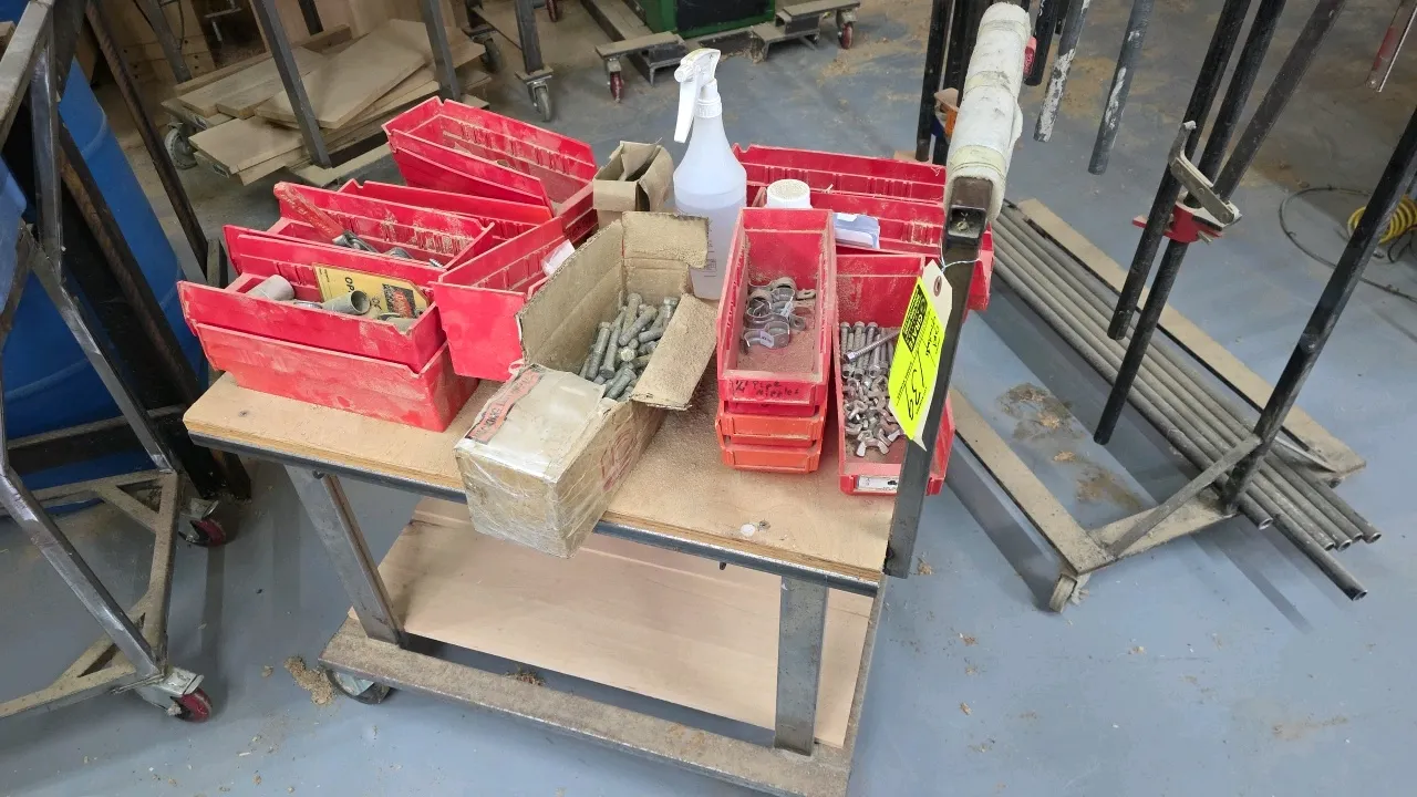 2-tier metal utility cart. Includes assorted red plastic storage bins with bolts, hardware, and fasteners. Features wood-top shelving and a push handl