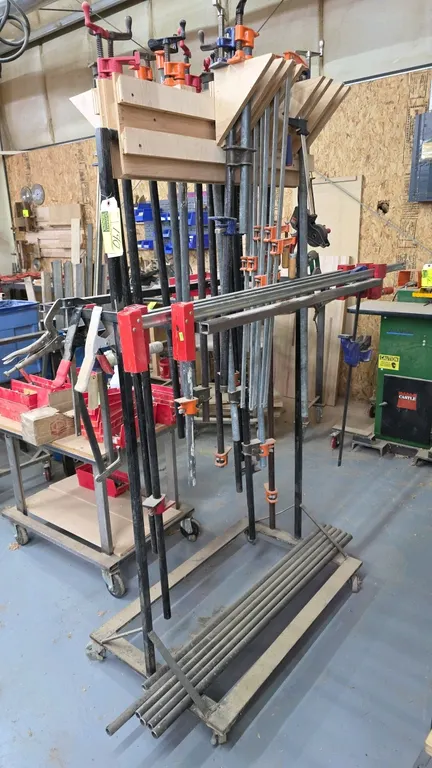 Assortment of clamps with mobile storage cart. Includes pipe clamps, bar clamps, locking clamp, and extra pipes. Cart features steel and wood construc