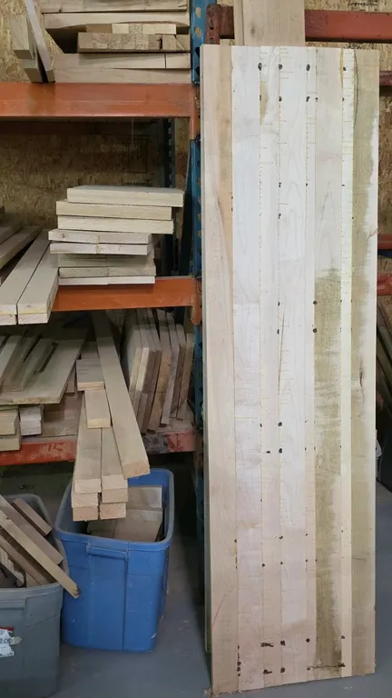 Assorted lumber cutoffs and wood panels. Features a variety of wood species, glued-up panels, dimensional boards, and scrap offcuts in assorted sizes.