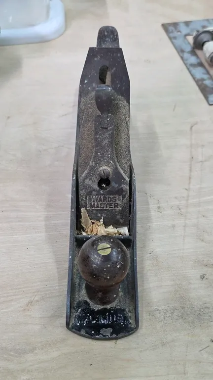 Wards Master No. 5 hand plane. Features a cast iron body, wooden rear tote, front knob, and adjustable blade mechanism. Made in USA.