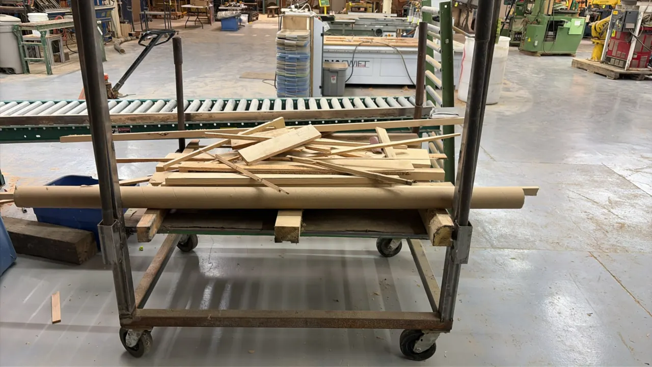 Portable metal material cart. Includes assorted wood pieces. 4' x 3'. Tubular steel construction with vertical upright posts. Mounted on casters.