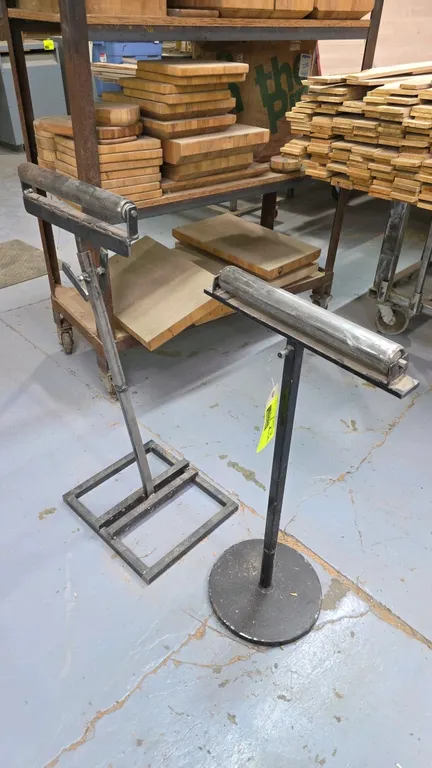 Metal roller material support stands. Features 15"W steel rollers and adjustable-height uprights mounted on round and rectangular metal bases.