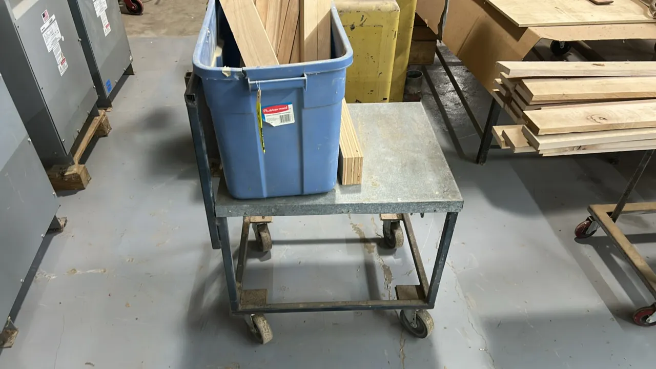 28" metal utility cart. Includes Rubbermaid plastic tote and quantity of assorted wood offcuts. Features integrated push handle and steel top platform