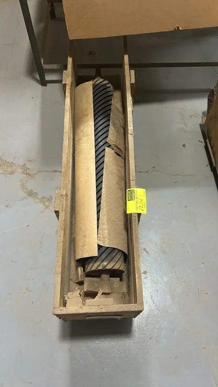 Industrial rubber-covered spiral contact drum roller. Features grooved rubber coating with shaft ends. Includes wooden storage crate.