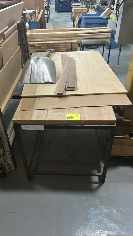 Metal frame work table with wood top and assorted wood. Features square steel tube base frame. 60" x 30". Shovel and background items not included.