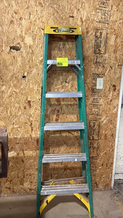 Werner 6' fiberglass stepladder. Features green fiberglass side rails, yellow molded top cap with tool slots, and slip-resistant aluminum steps.