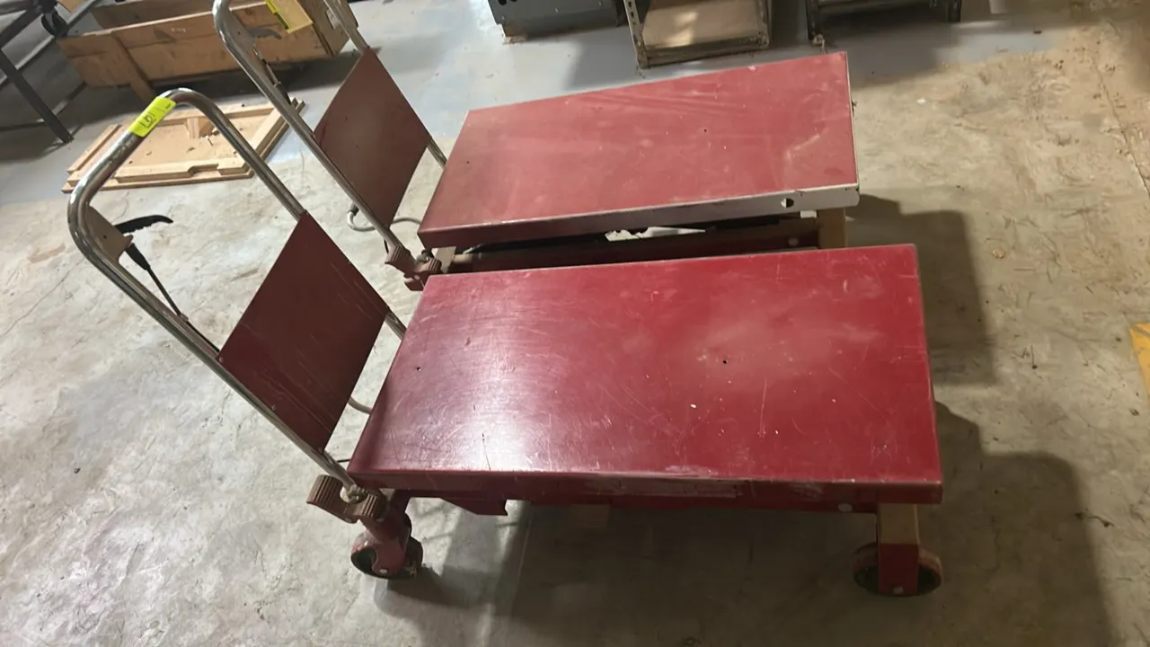 Uline manual hydraulic lift table cart. Features foot pedal pump operation, hand release lever, and chrome push handle. 44"L. Mounted on casters.