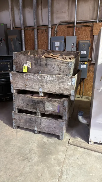 Set of (4) wooden dump skids with assorted wood cutoff scraps. Features stackable wooden crate construction with metal corner reinforcement brackets.