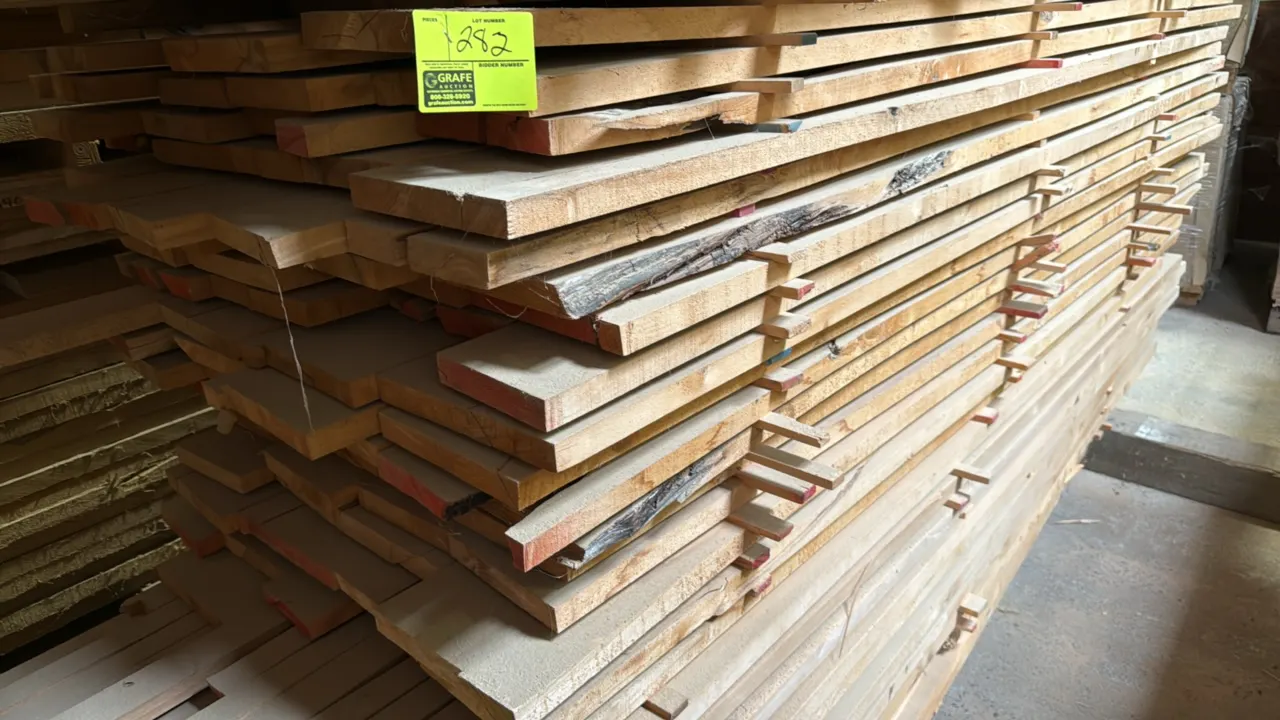 Skid of assorted wood boards. Features rough-cut lumber with 1.25" thickness, stacked with wooden spacers. Overall stack measures approximately 8' x 3