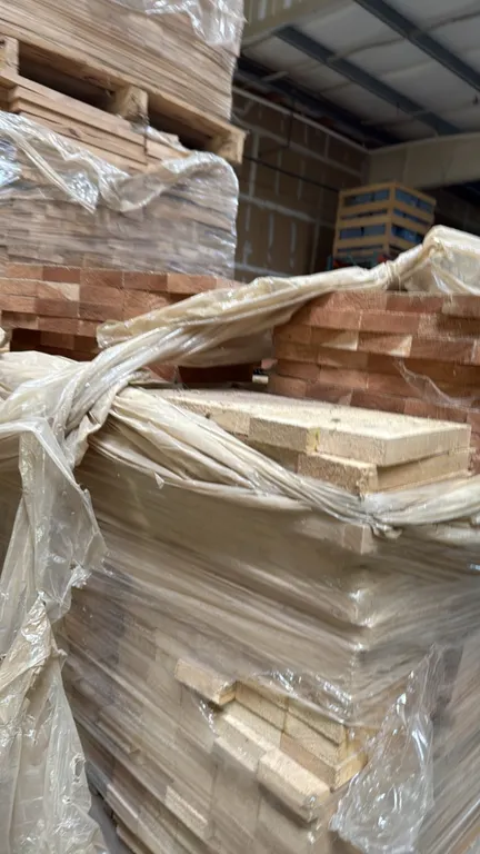 Pallet of glued alder cut stock boards. Stacked and shrink-wrapped on a wooden pallet.