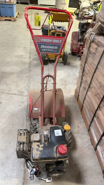 Troy-Bilt Bronco CRT rear-tine rototiller. Features counter-rotating tines, gas-powered OHV engine with recoil start, protective tine shield, loop han