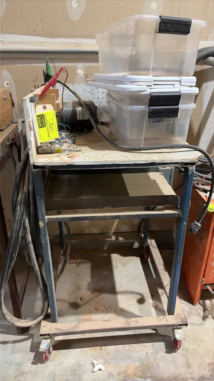Portable work table. Features wooden work top, metal frame, integrated side electrical box, and extension cords. 2' x 2'. Mounted on swivel casters. C