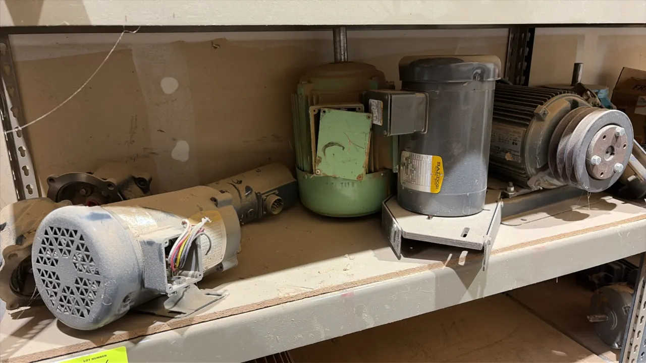 Assorted industrial electric motors across 3 shelf rows. Includes various frame sizes, makes including Baldor, and configurations with pulleys and mou