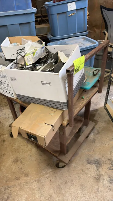 Metal 4-wheel utility cart with assorted contents. Includes electrical parts, cables, computer components, and miscellaneous sundries. Features a stee