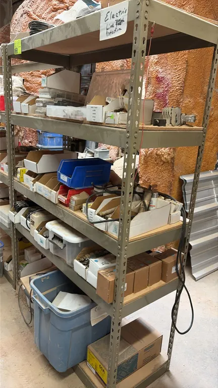 5-tier metal shelving rack with assorted electrical components and parts. Features particle board decking and adjustable keyhole uprights. Includes bi