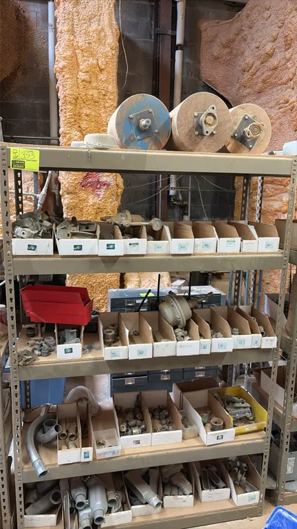 Metal storage rack with electrical parts and wood drums. Includes 5-shelf metal racking unit with organizer bins containing assorted electrical condui