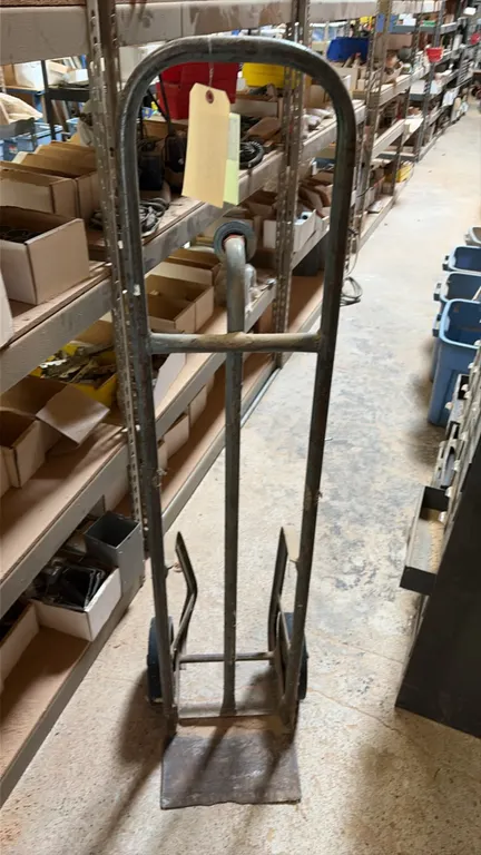 2-wheel hand truck dolly. Features tubular steel frame construction, loop handle, center vertical support, and solid steel nose plate. Mounted on two