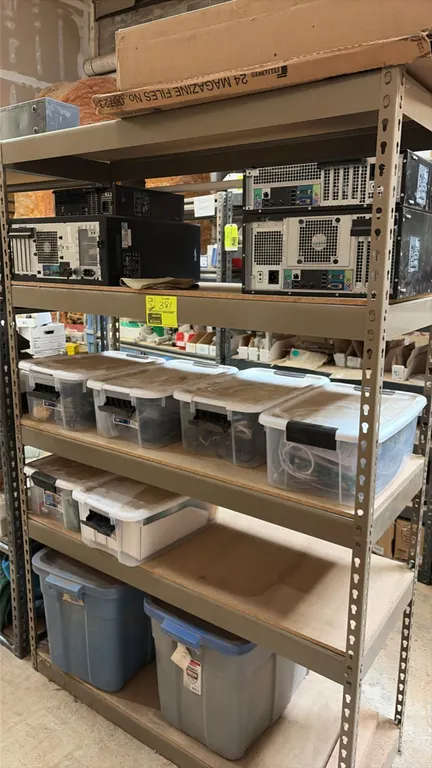 Metal storage rack with assorted computer components. Includes 5-tier metal frame shelving unit, desktop PC towers, clear and solid plastic storage to