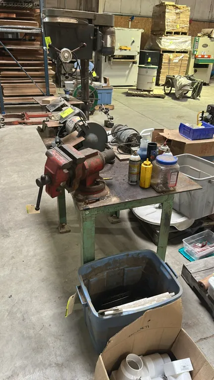 Multi-purpose bench vise mounted on a metal work table. Features rotating jaws, built-in pipe jaws, integrated anvil, and a swivel base. Metal work ta