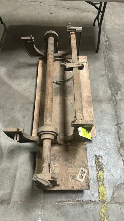 Wood lathe duplicator attachment. Features cast metal mounting brackets, tubular support shaft, and adjustable follower rail assembly. Resting on a wo