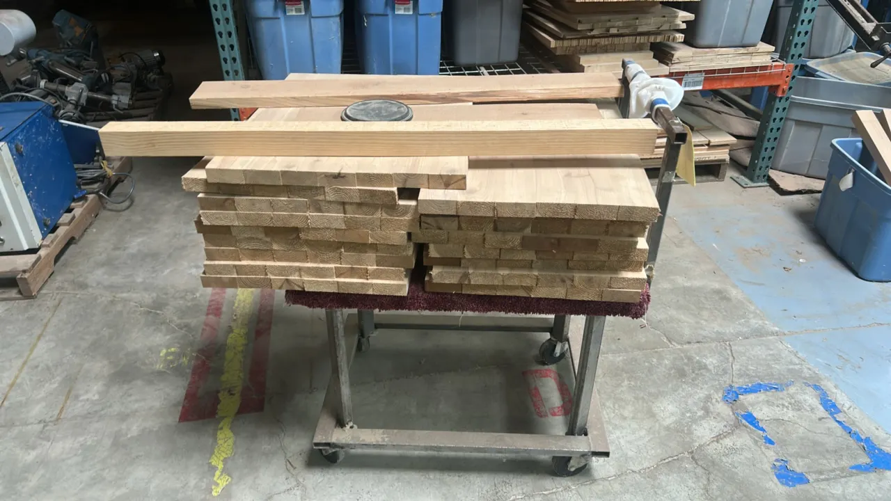 30" metal cart with quantity of wood. Features tubular steel construction, padded deck, push handle, and caster wheels. Includes an assortment of cut
