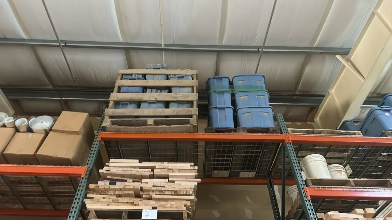 Assorted blue plastic storage totes. Features molded polyethylene construction with matching lids. Palletized. Pallet racking, lumber, and surrounding