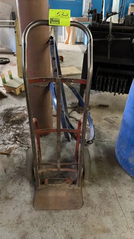 Two-wheel hand truck dolly. Features tubular metal frame, continuous loop handle, nose plate, and (2) solid rubber wheels.