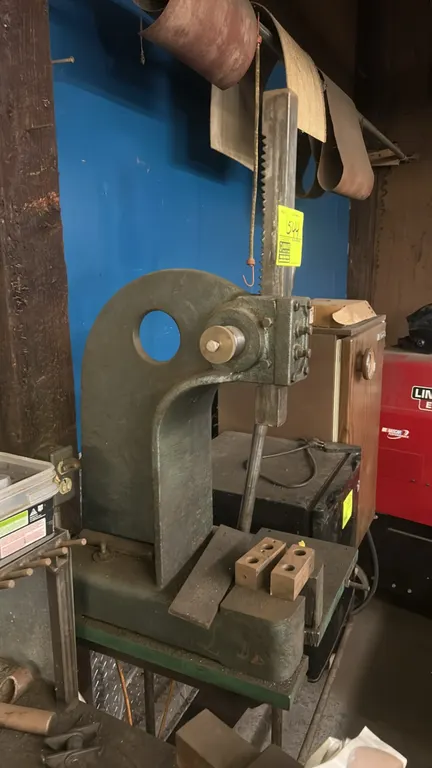Enco manual arbor press. Features cast iron frame construction, square toothed ram, and lever handle. Includes steel riser blocks. Workbench and backg