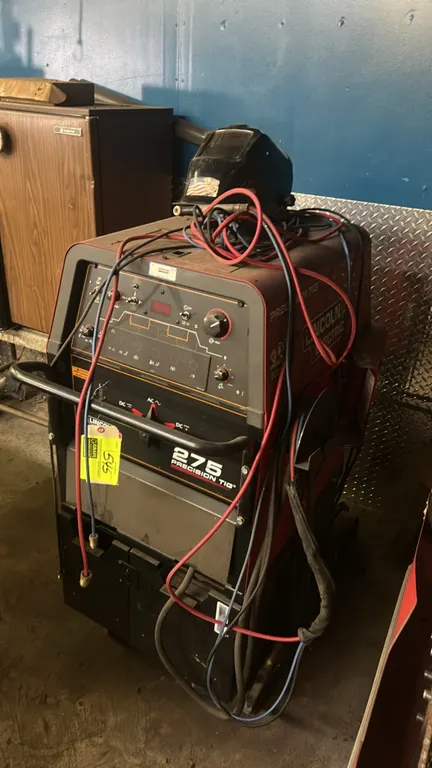 Lincoln Electric Precision TIG 275 AC/DC TIG and stick welder. Includes TIG torch, leads, and welding helmet. Features AC/DC selector and front contro