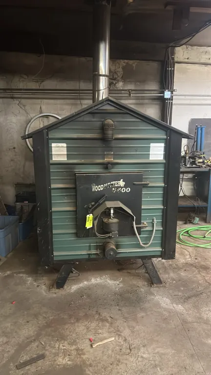 WoodMaster 4400 outdoor wood furnace. Features a 38" x 44" firebox, 24" x 24" fuel door, 112-gallon water capacity, and a forced-air draft control fan