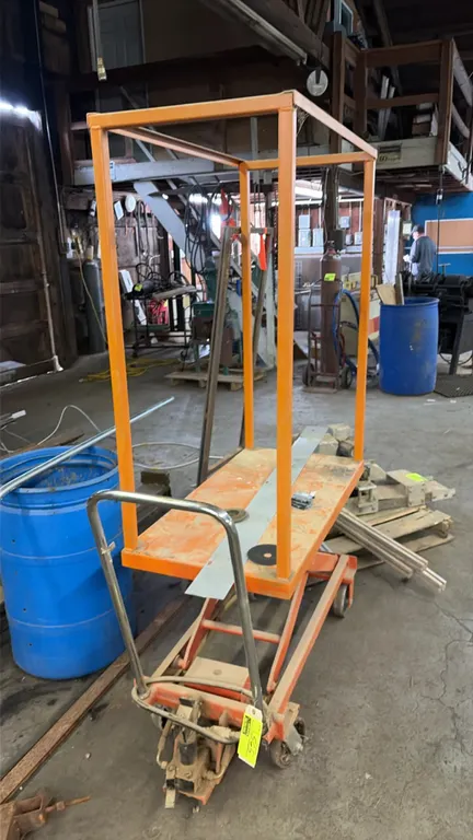 Mobile hydraulic scissor lift cart. Features steel construction, foot-pedal hydraulic lift mechanism, upper tubular frame, and chrome push handle. Mou