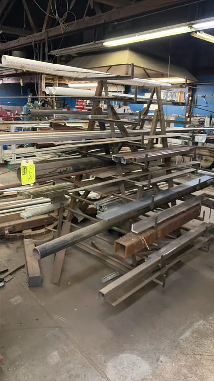 Metal A-frame bar and pipe storage rack with assorted material stock. Features multi-tier cantilever arms, steel frame mounted on casters, and include