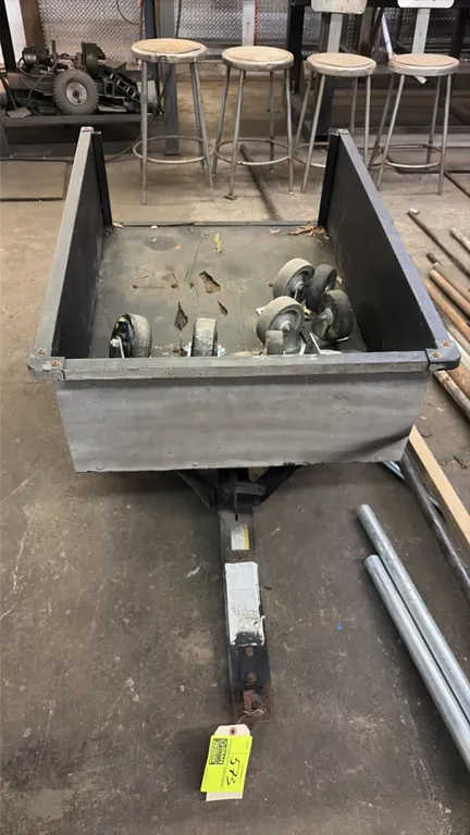 Metal tow-behind lawn cart trailer. Features steel cargo bed and pneumatic tires. Equipped with a tow hitch tongue. Contents not included.