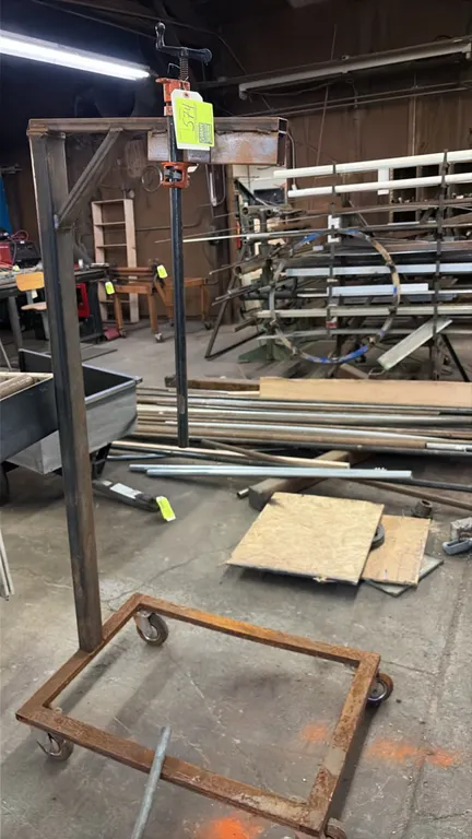 Custom fabricated mobile hoist stand. Features welded tubular steel construction with an integrated overhead pipe clamp assembly. Mounted on a 4-wheel