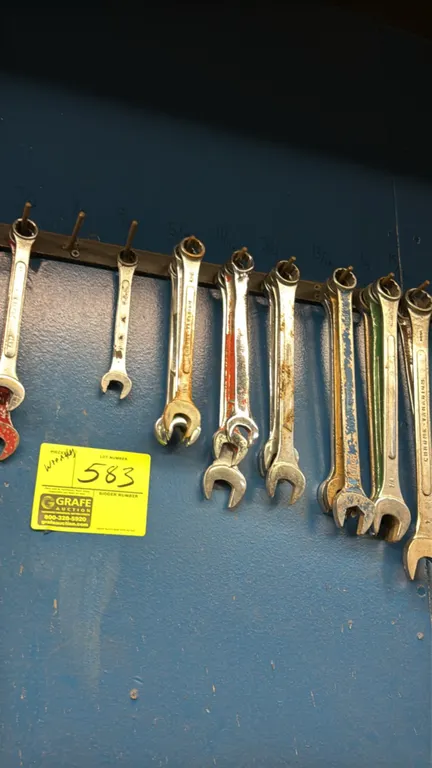 Assorted combination and open-end wrenches. Features various sizes and styles. Note: Wall rack, clipboard, and whiteboard not included.