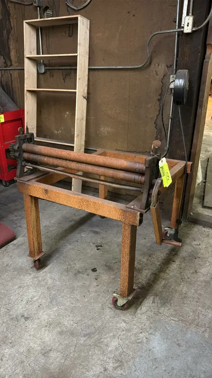 Manual sheet metal slip roll. 31" roll width. Features a 3-roll design with manual hand crank and dual adjustment screws. Mounted on a steel stand wit
