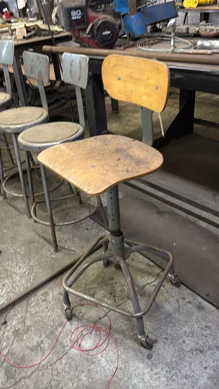 Industrial metal shop stools. Includes (4) stationary metal stools with circular inset seats, integrated foot rings, and tubular steel legs (3 with ba