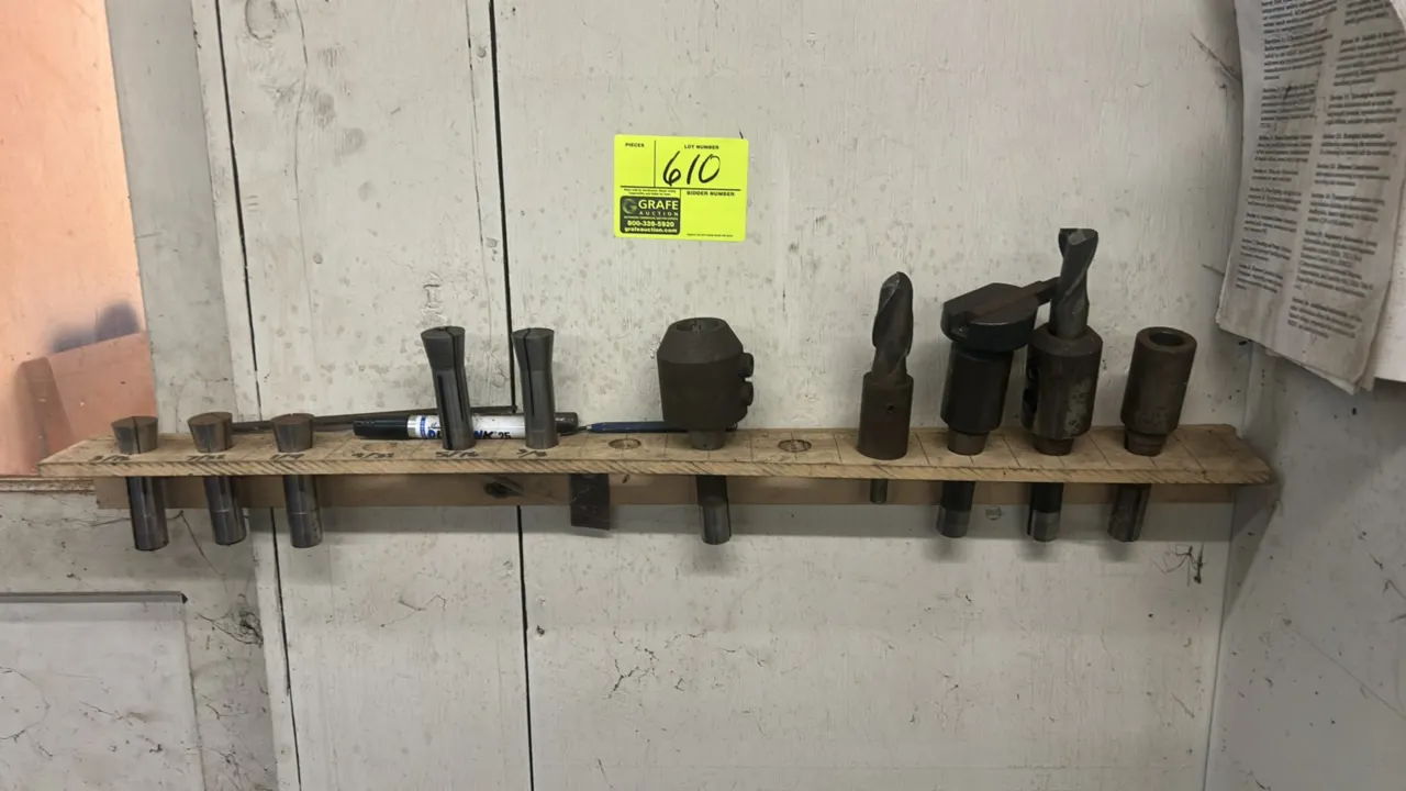 Machining tooling and accessories assortment. Includes assorted collets, tool holders, milling cutters, drill bits, and wooden storage rack.