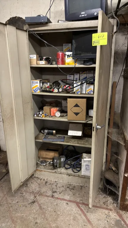 Metal 2-door storage cabinet with assorted parts. Features double doors and multiple interior shelves. Includes assorted contents such as NAPA oil and
