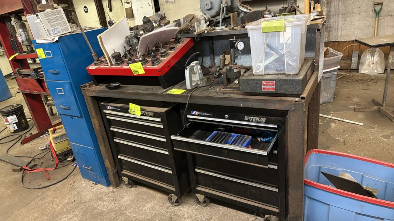 64"L metal workbench with Starrett Grade B granite surface plate. Features heavy-duty tubular steel frame construction and upper shelf riser. Plate Nu