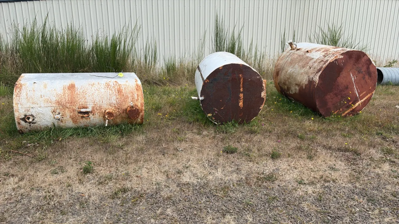 Metal storage tanks. Welded steel construction with threaded pipe fittings and bungs. Note: Units exhibit heavy rust throughout.