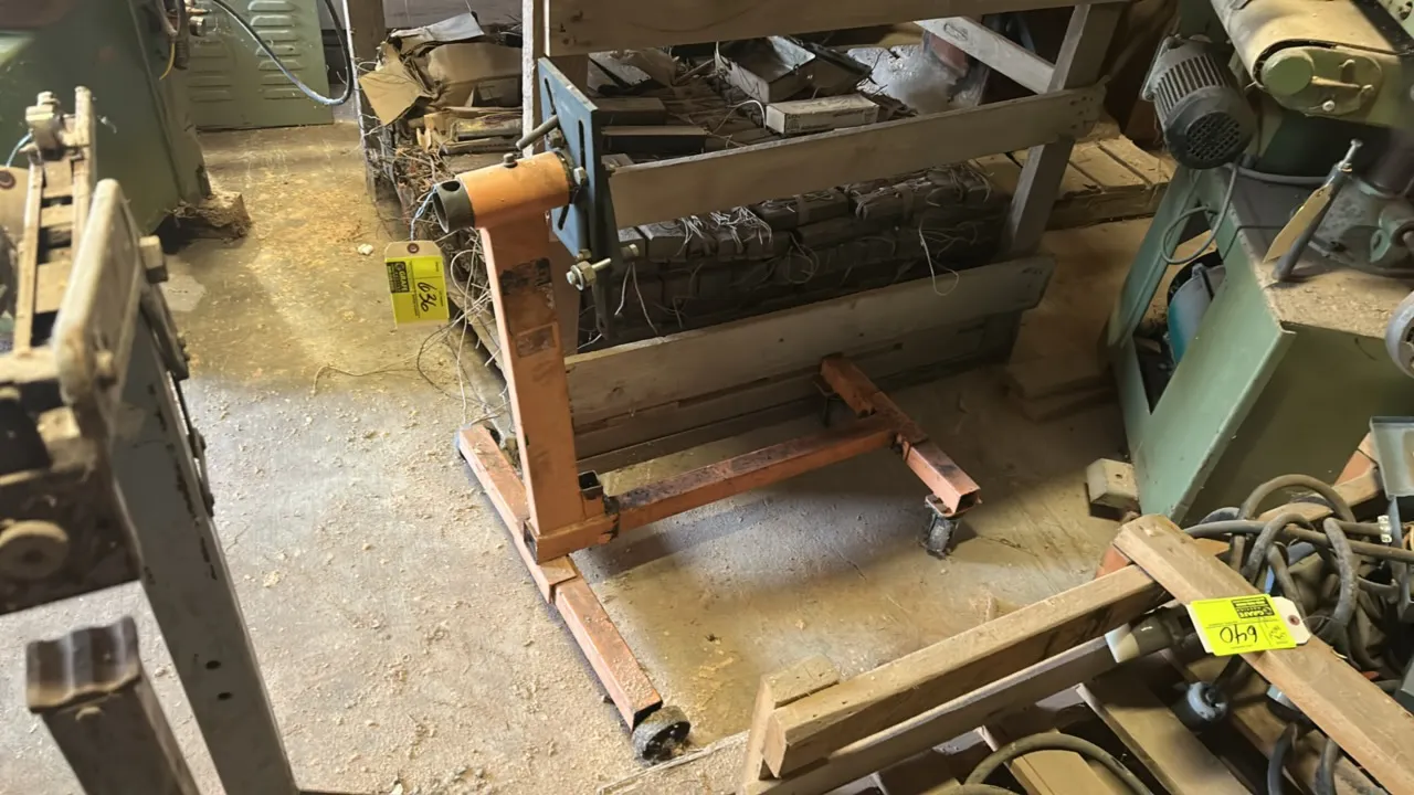 Mobile engine stand. Features an orange steel frame, rotating mounting head with adjustable arms, and a mobile base. Mounted on casters.