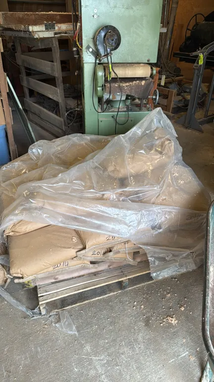 Pallets of bagged sandblasting abrasive media. Includes assorted bags marked 40/70 and 20/40. Stored on wooden pallets. Background items and storage t
